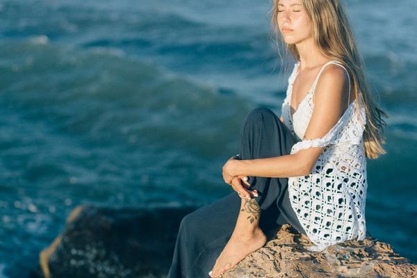 Woman meditating in a serene environment, eyes closed.